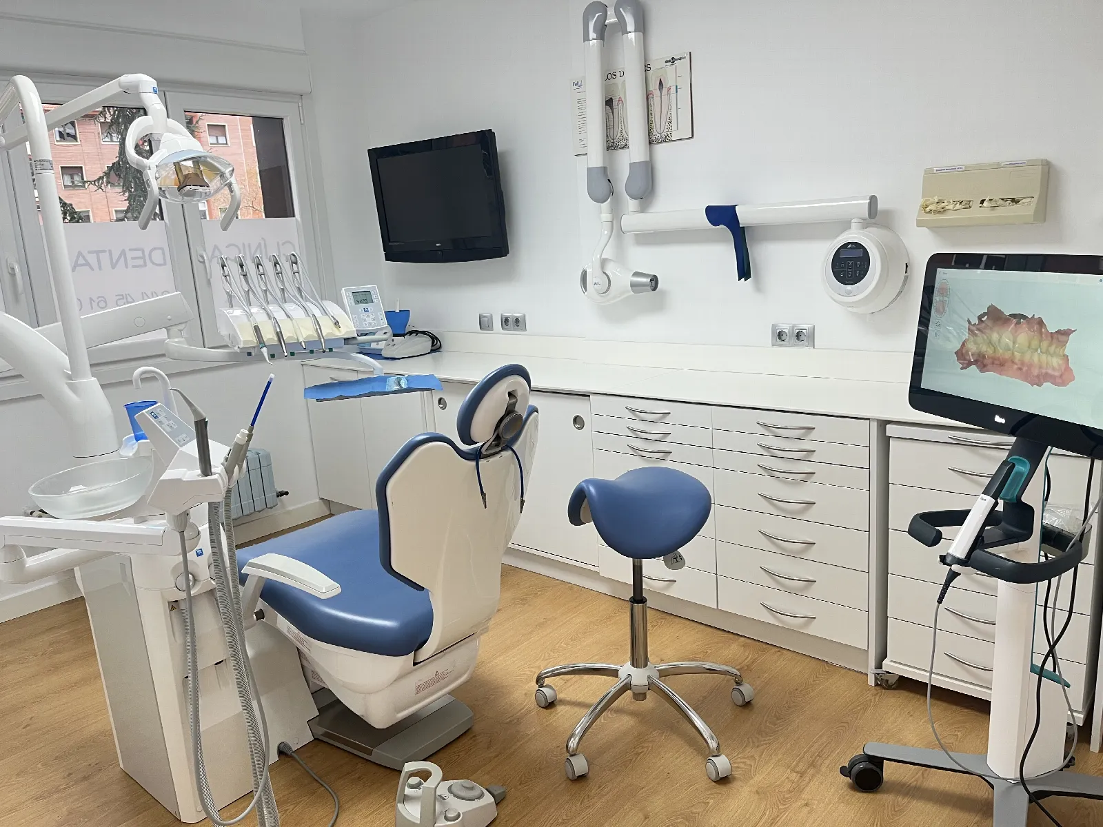 Un gabinete de la clínica, con el sillón azul, el taburete y el escáner intraoral con su pantalla